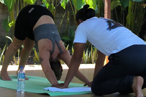 Yoga instructor assisting woman in downward dog pose