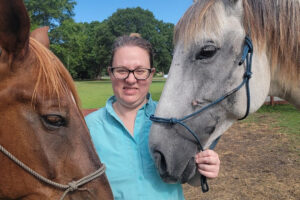 Woman standing between two horses outdoors