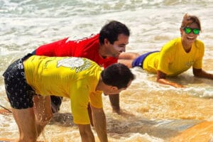 Three people laughing during a surf lesson