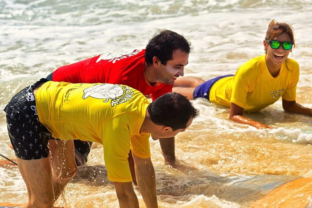 Three people laughing during a surf lesson