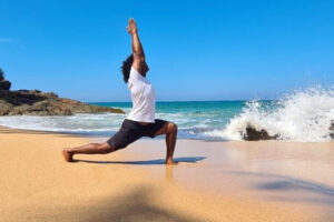 Person practicing yoga lunge on sunny beach