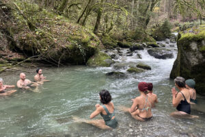 People bathing in forest river near waterfall