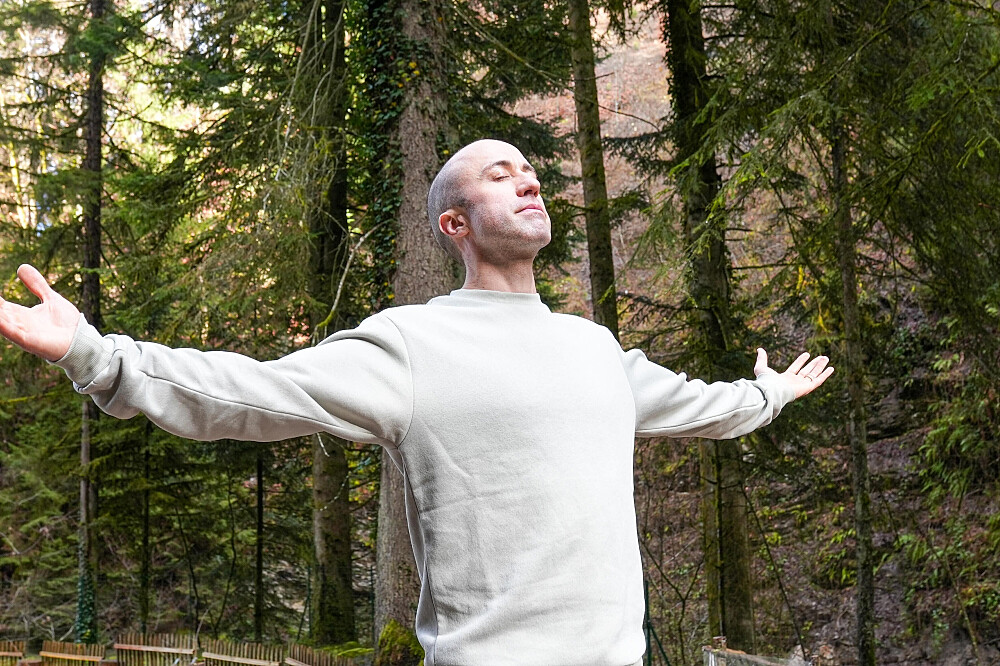 Man with arms outstretched in forest