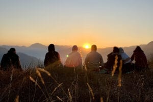 Friends watching sunset over mountain landscape