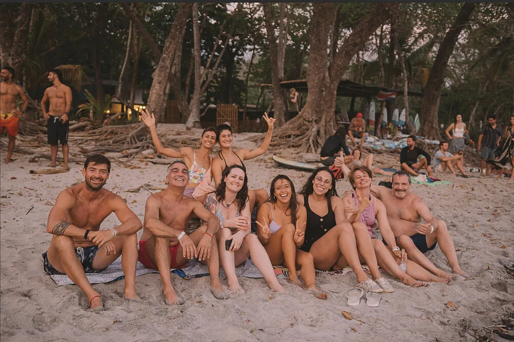 Een groep vrienden lacht op een tropisch strand.