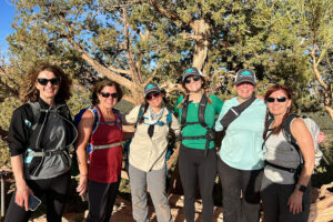 Six women hikers posing on sunny trail