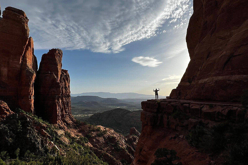 Hiker standing on cliff overlooking red rock canyon