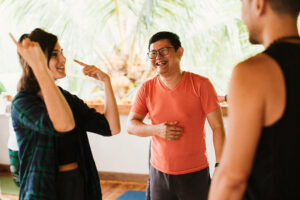 Three adults laughing during indoor yoga class