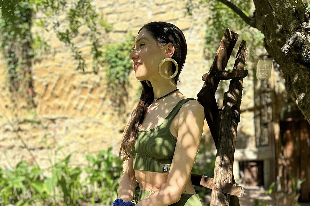 Woman in green top standing in sunny garden