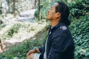 Man relaxing with eyes closed in forest