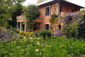 Peach villa surrounded by lush blooming garden