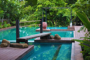 Modern tropical pool with wooden deck and bench