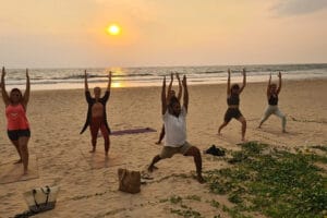 Group practicing yoga on beach at sunset