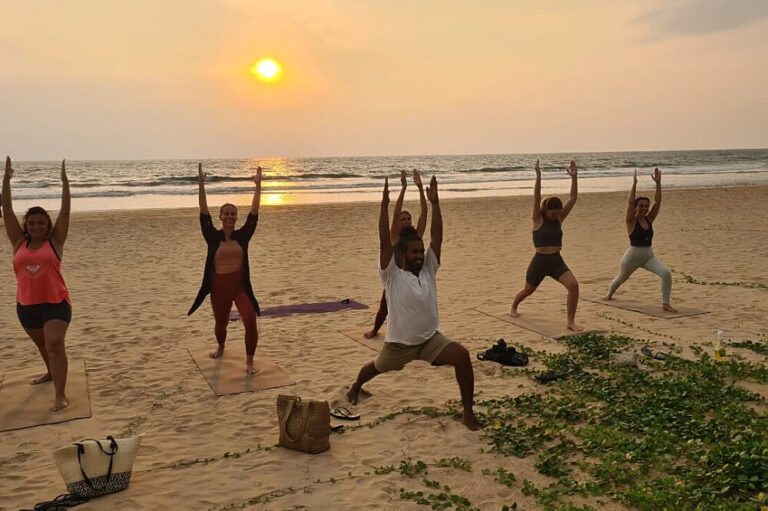 Group practicing yoga on beach at sunset