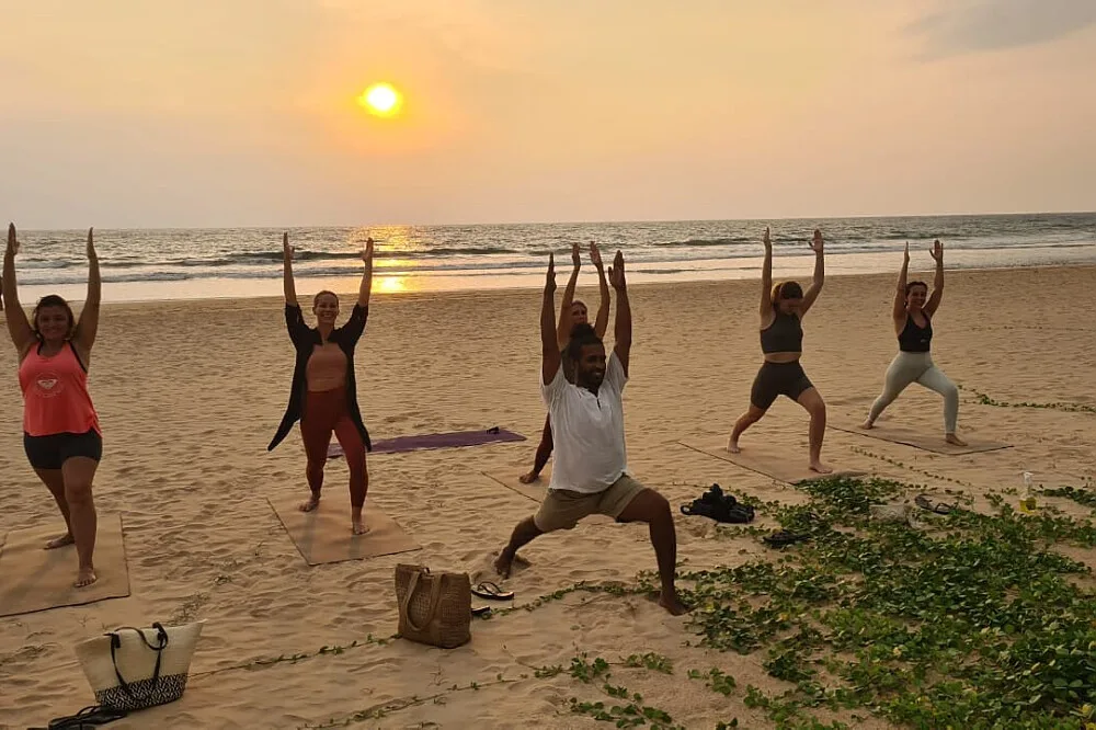 Group practicing yoga on beach at sunset