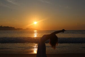 Silhouette stretching on beach at sunset