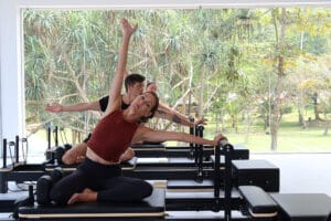 Three people doing Pilates on reformer machines