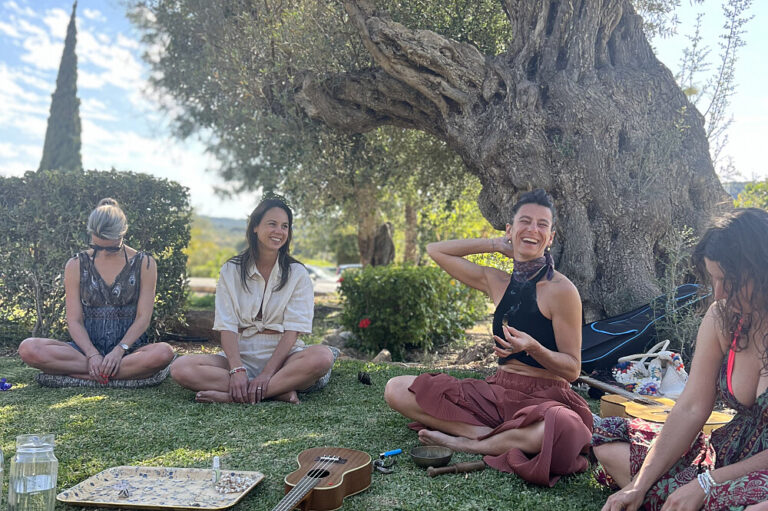 Women sitting on grass under tree with ukulele