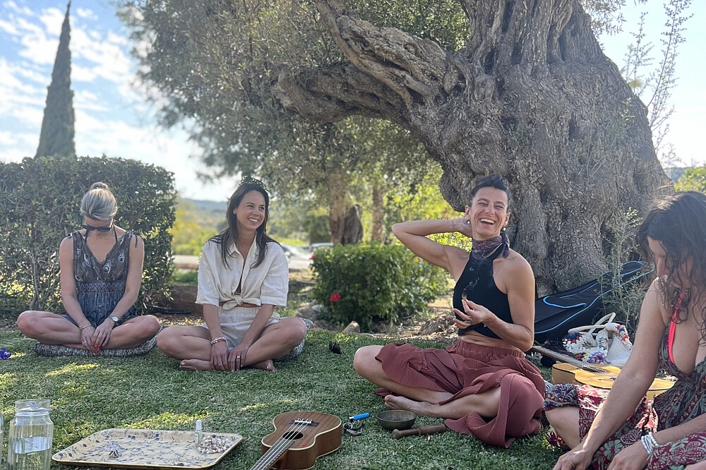 Women sitting on grass under tree with ukulele