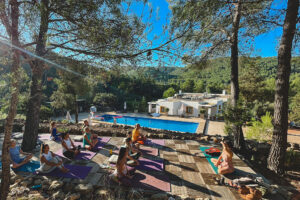 Outdoor yoga class overlooking pool and forested hills