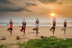 Group practicing yoga on beach at sunset