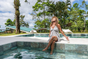 Woman relaxing by tropical pool in summer dress