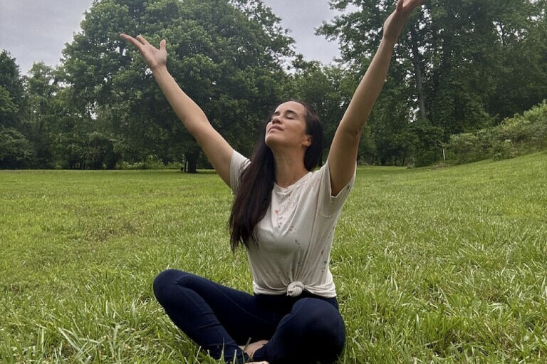 Woman meditating with arms raised in park