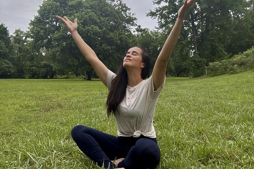 Woman meditating with arms raised in park
