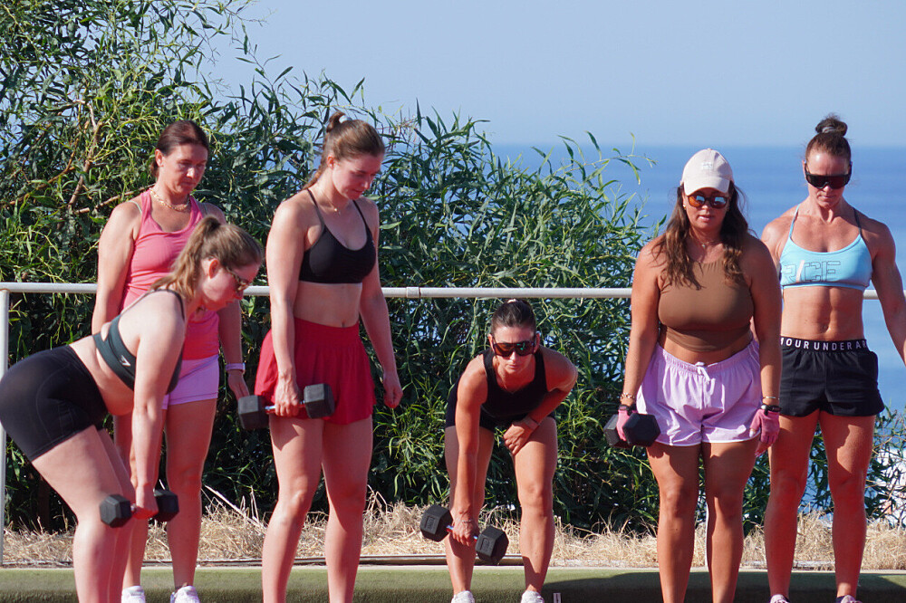 Women exercising outdoors with dumbbells by the ocean