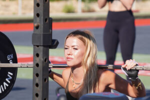Woman performing barbell squat outdoors