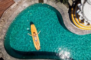 Woman floating on surfboard in turquoise pool