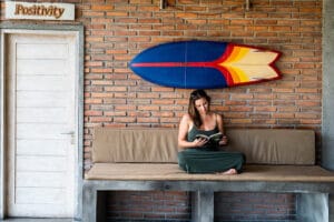 Woman reading on bench beneath surfboard wall decor