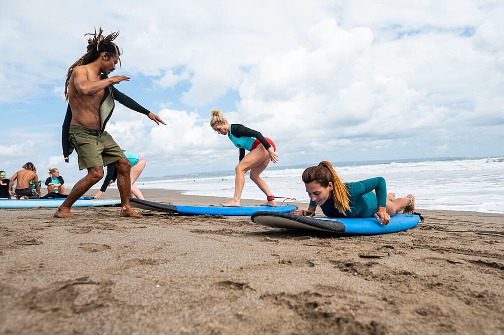 Surf instructor teaching students on sandy beach