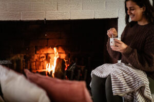 Woman enjoying warm drink by cozy fireplace