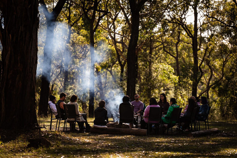 Group sitting around campfire in forest clearing