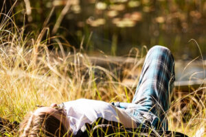 Person relaxing on grass by a lake