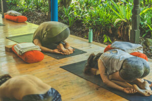 People practicing yoga on outdoor wooden deck