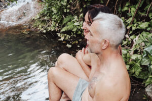 Couple sitting by lush forest stream waterfall