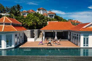 Group yoga session on poolside deck at luxury villas
