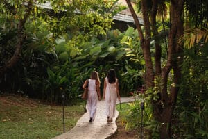Two women walking through lush tropical garden path