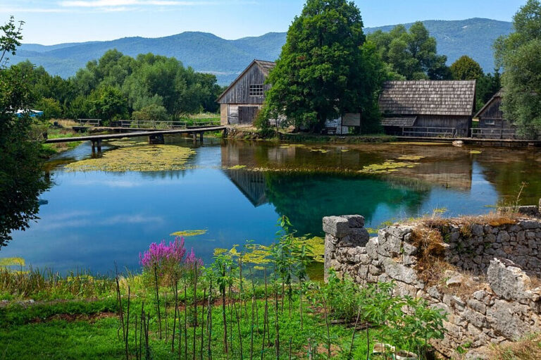 Rustic wooden houses beside clear mountain pond