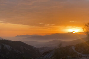 Sunset over layered mountains with winding road