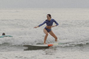 Woman surfing small ocean wave in blue swimsuit