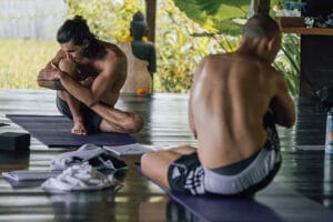 Two men stretching on yoga mats indoors