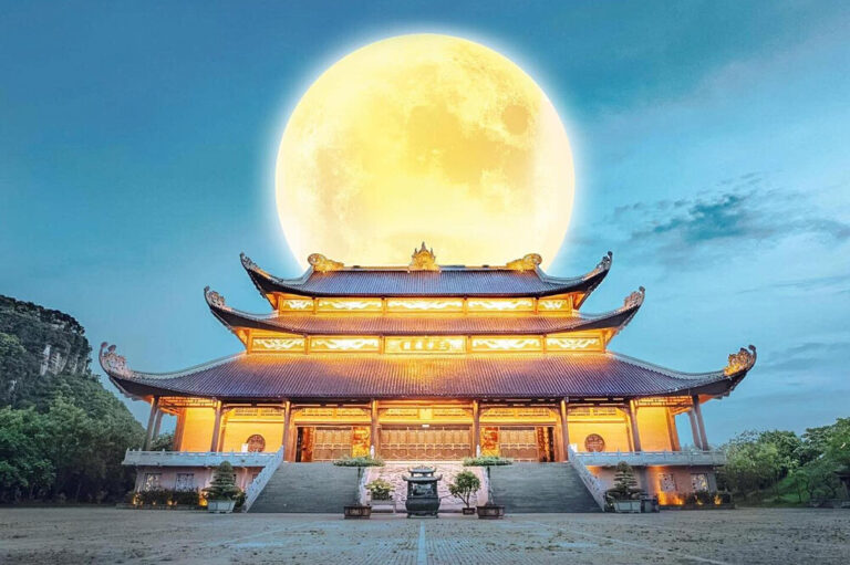 Illuminated Chinese temple with full moon backdrop