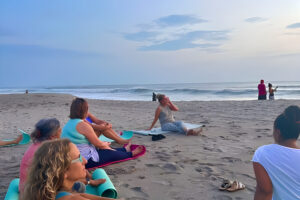 Beach yoga class at sunset by ocean