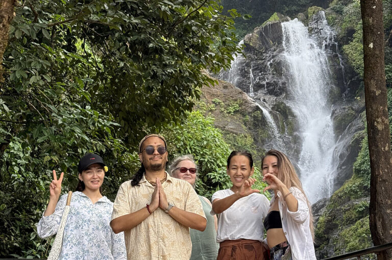 Group posing before lush waterfall