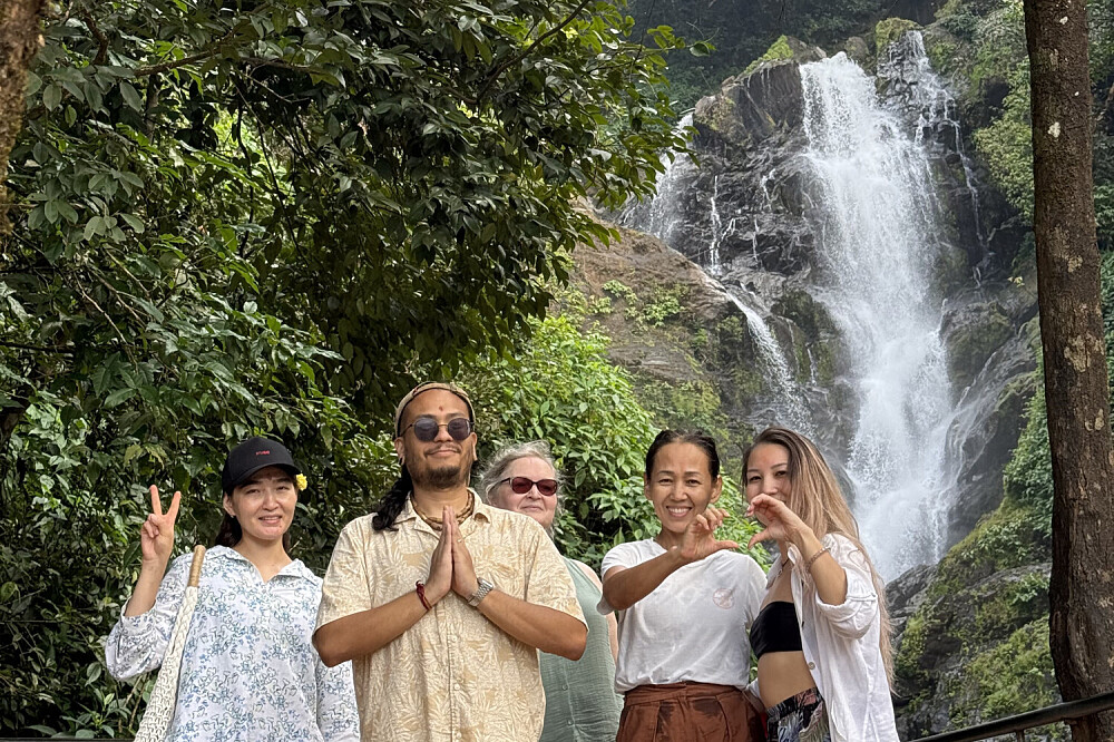 Group posing before lush waterfall