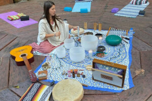 Woman playing singing bowls on outdoor wooden deck
