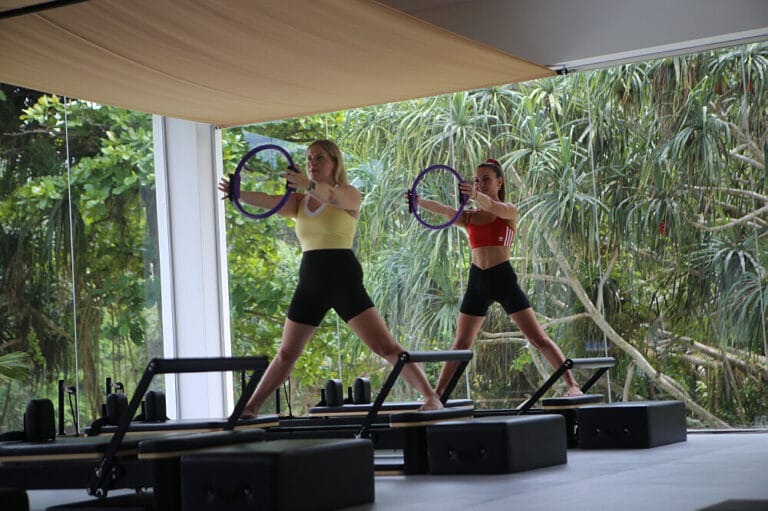 Two women doing Pilates with rings indoors